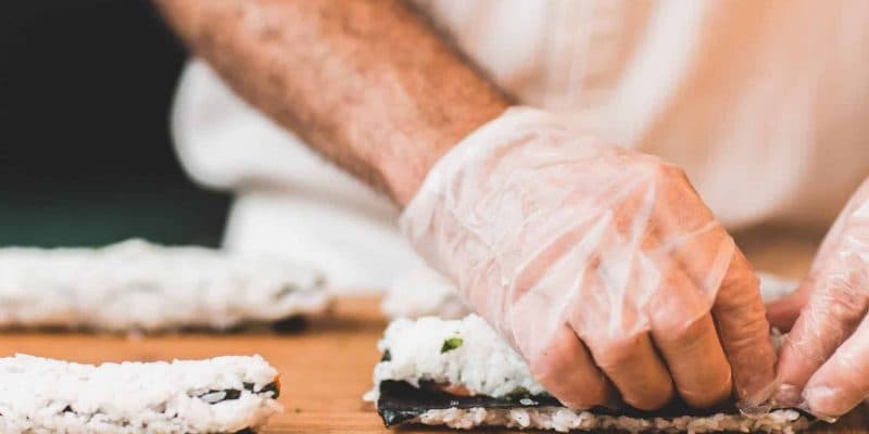 uomo con guanto bianco monouso che prepara il sushi
